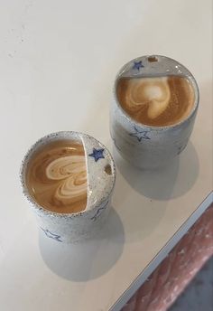 two cups with liquid in them sitting on a table