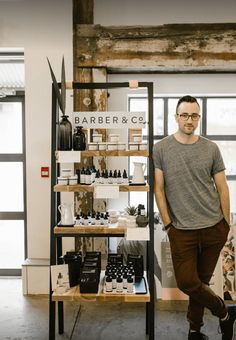 a man standing in front of a shelf with bottles and other items on it's shelves