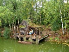 a man sitting on top of a wooden dock next to a small boat in the water