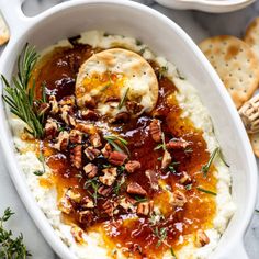 mashed potatoes topped with pecans and gravy in a white serving dish