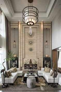 a living room filled with white couches and chairs next to a fire place under a chandelier