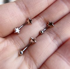 three tiny silver stars are on the finger of someone's left hand and they appear to be piercing