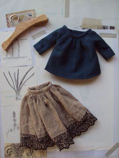 a doll's clothes and accessories are laid out on top of a piece of paper