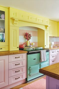 an old fashioned stove in a kitchen with pastel cabinets and pink rug on the floor