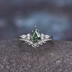 a close up of a ring with a green stone in the middle and diamonds around it