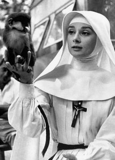 a woman dressed in nun costume holding a monkey on her hand