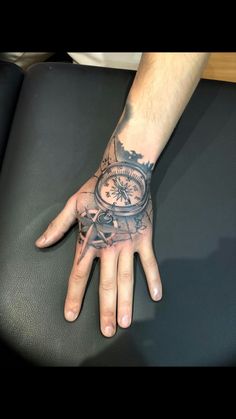 a man's hand with a compass tattoo on it