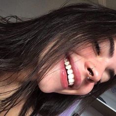 a woman with long hair and piercings smiling