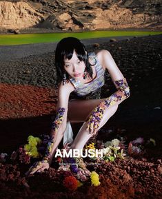 a woman kneeling down in the dirt with her hands on her knees and flowers all over her body