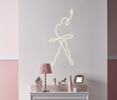 a white fireplace with a neon light drawing on the wall above it and a pink lamp next to it