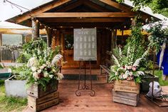 an outdoor wedding venue with flowers and greenery in wooden boxes on the ground, surrounded by string lights