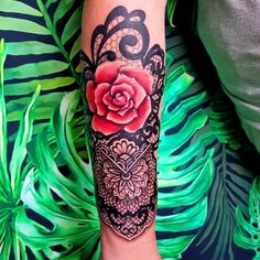 a woman's arm with a rose and snake tattoo on it, surrounded by leaves