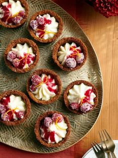 small desserts are arranged on a platter with silverware and red napkins