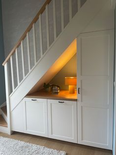 an under the stairs storage area with drawers and cupboards in white painted wood flooring