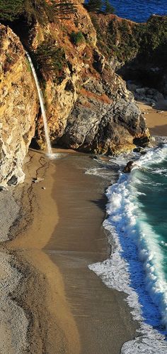 an ocean beach with waves crashing on the rocks and water coming out of the cliff