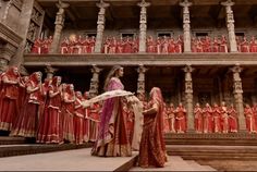 a group of women dressed in red and gold standing next to each other on stairs