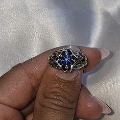 a woman's hand holding a ring with an intricate design on it, in front of a white background