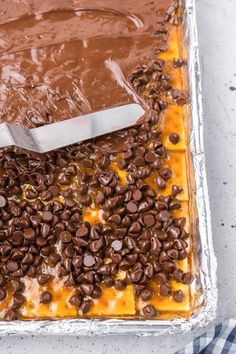 a cake with chocolate and caramel toppings on it, being cut by a knife