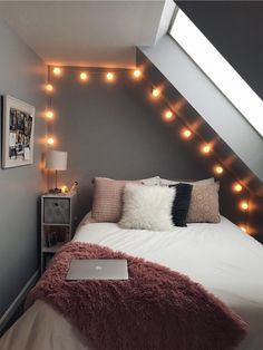 a bedroom with lights on the wall and a laptop on the bed in front of it