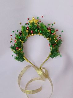 a christmas wreath with gold and green decorations on it's headband, next to a white ribbon