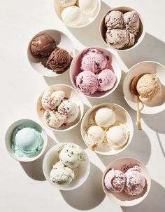 bowls of ice cream are arranged on a white surface