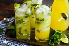 three glasses filled with lemonade and mint on a tray