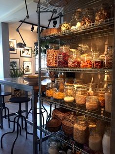 the shelves are filled with many different types of food and drink in glass jars on metal racks