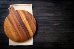 a wooden cutting board sitting on top of a white and black checkered napkin next to a knife