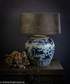 a blue and white vase sitting on top of a wooden table next to a lamp