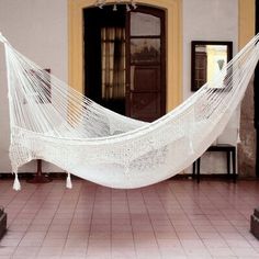 a white hammock hanging from the ceiling in a room with red tile flooring