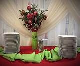 a table topped with plates covered in green cloths and vase filled with red flowers