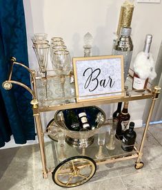 a bar cart with wine glasses and bottles on it