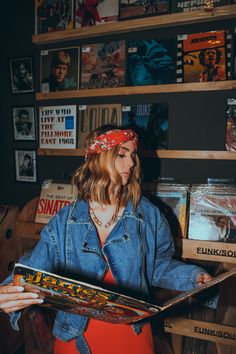 a woman in a denim jacket and bandana is holding a record player's case