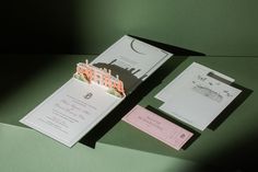 the wedding stationery is laid out on top of the green table with matching envelopes