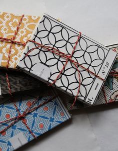 four books tied together with twine on top of each other in different patterns and colors