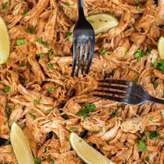 shredded chicken with lemon wedges and parsley on the fork in a skillet