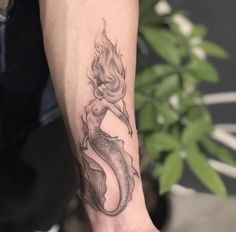 a woman's arm with a mermaid tattoo on it