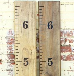 two wooden rulers with numbers on them sitting next to a brick wall in front of a red brick wall