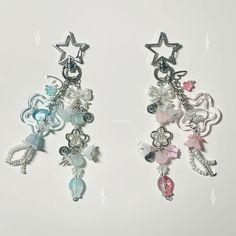 two pairs of earrings with charms attached to them on a white surface, one has a star and the other has beads