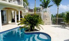 an outdoor swimming pool with stairs leading to the upper floor and second story balcony area