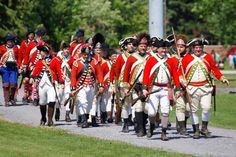 a group of men in red and white uniforms marching down a road