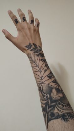 a person's arm with tattoos on it, and one hand in the air