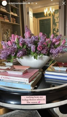 a table topped with books and a vase filled with purple flowers on top of it