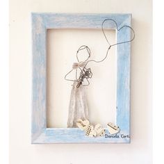 a blue frame with a string angel hanging from it's side and two hearts attached to the inside