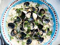 a bowl filled with clams and greens on top of a table