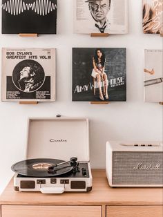 an old record player sitting on top of a wooden table next to pictures and speakers