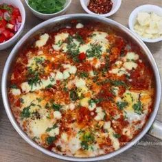 a pizza in a pan with toppings on the side and other dishes around it