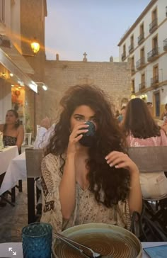 a woman sitting at a table with a plate and cup in front of her face