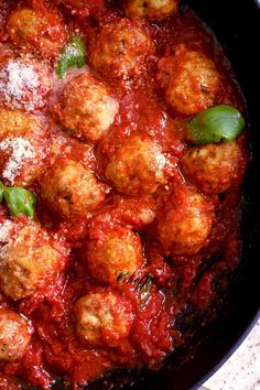 meatballs and sauce in a skillet on a stove top with green pepper sprinkles