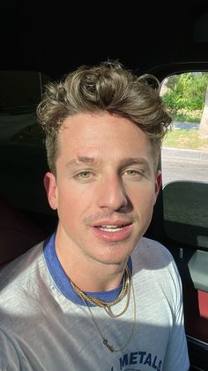 a man with blonde hair sitting in the back seat of a car looking at the camera